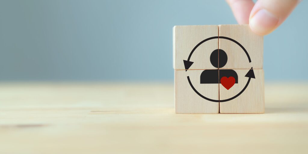 mano poniendo pieza de puzzle representado con el emoticono de usuario con corazon